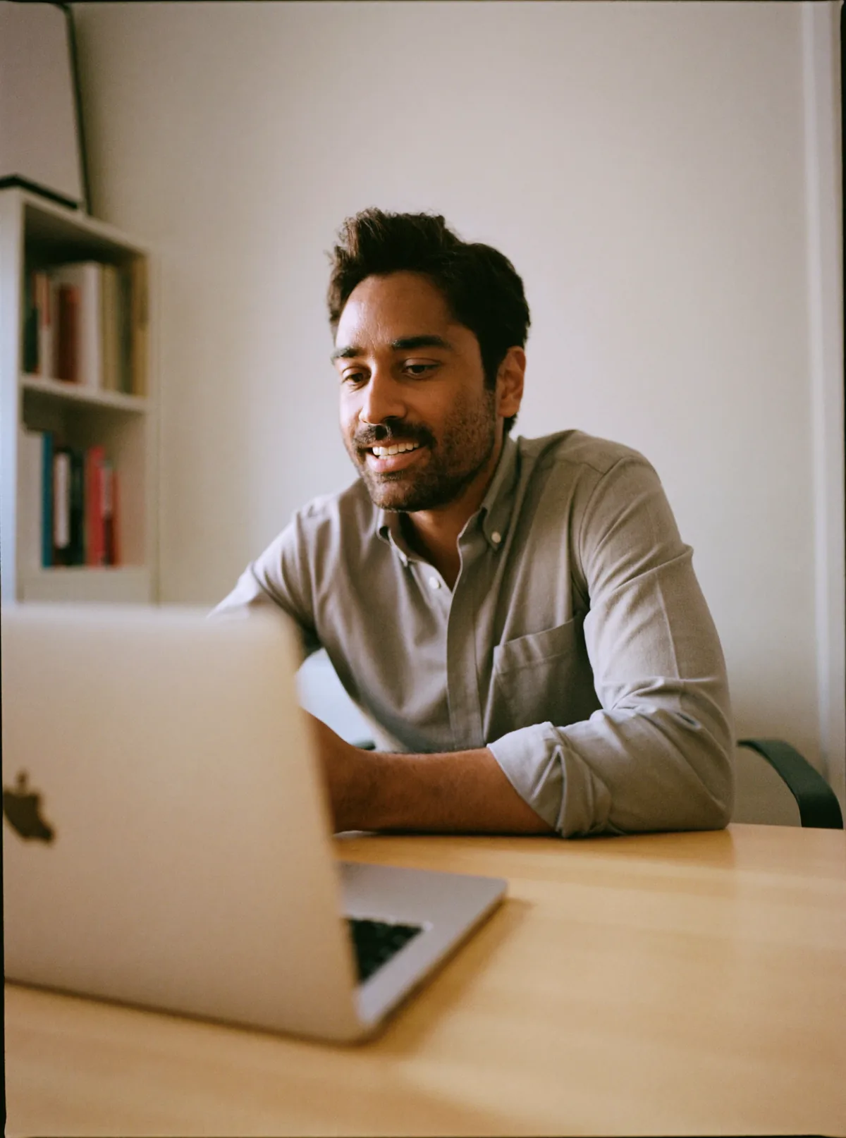 A young man smiles during a video call on his laptop.