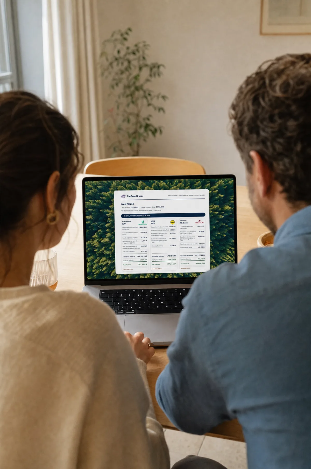 A couple at a wooden table reviewing TheGoodBroker's tariff shortlist together on a laptop.
